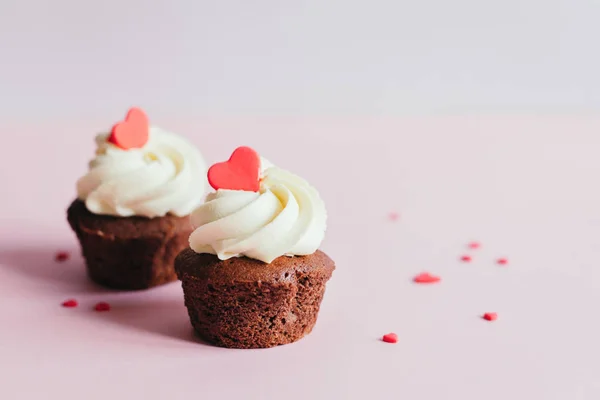 Cupcakes Valentine, decorados com corações doces em fundo pastel rosa . — Fotografia de Stock