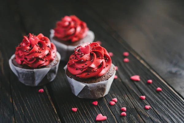 Cupcakes Valentine na cor vermelha, decorados com corações doces na mesa de madeira escura . — Fotografia de Stock