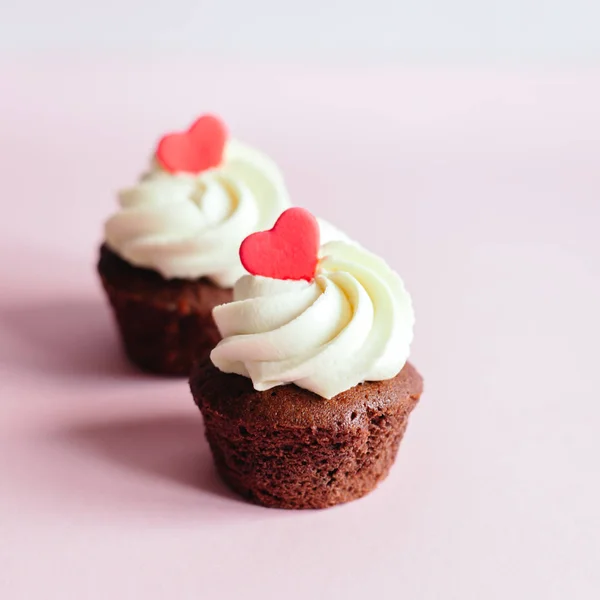Cupcakes Valentine, decorados com corações doces em fundo pastel rosa . — Fotografia de Stock