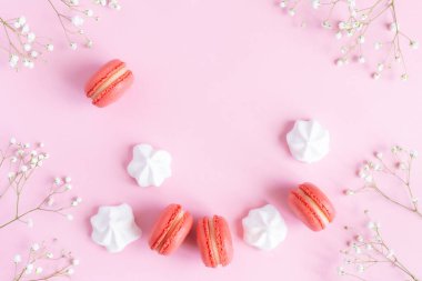 Pembe badem kurabiyeleri, beyaz şekerlemeler ve pembe pastel arka planda çiçekler.. 