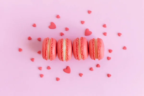 Sabrosos macarrones franceses sobre un fondo rosa, decorados con corazones dulces . — Foto de Stock