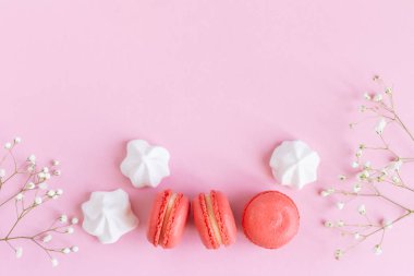 Pembe badem kurabiyeleri, beyaz şekerlemeler ve pembe pastel arka planda çiçekler.. 