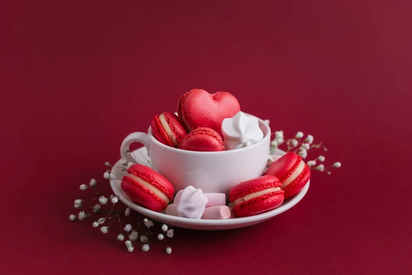 Fondo del día de San Valentín con macarrones y malvaviscos rojos en forma de corazón. Copa con macarrones y malvaviscos . — Foto de Stock