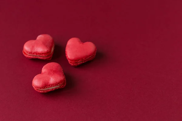 Macarrones en forma de corazón sobre un fondo rojo oscuro. Concepto para el Día de San Valentín . — Foto de Stock