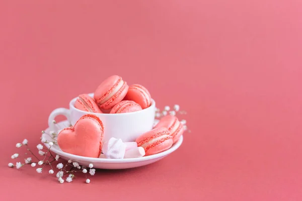 Fondo del día de San Valentín con macarrones y malvaviscos en forma de corazón francés rosado. Copa con macarrones y malvaviscos . — Foto de Stock