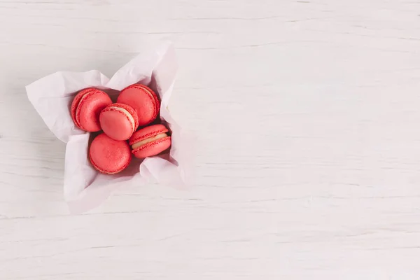 Macarons franceses rojos en una caja sobre un fondo de madera blanco. Concepto para el día de San Valentín . — Foto de Stock