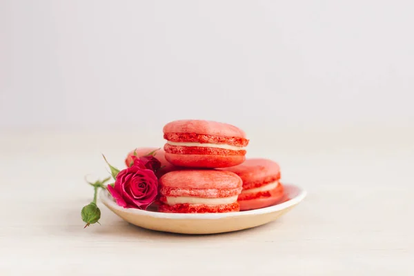 Lekkere Franse Macarons Met Roze Rozen Een Bord Witte Achtergrond — Stockfoto