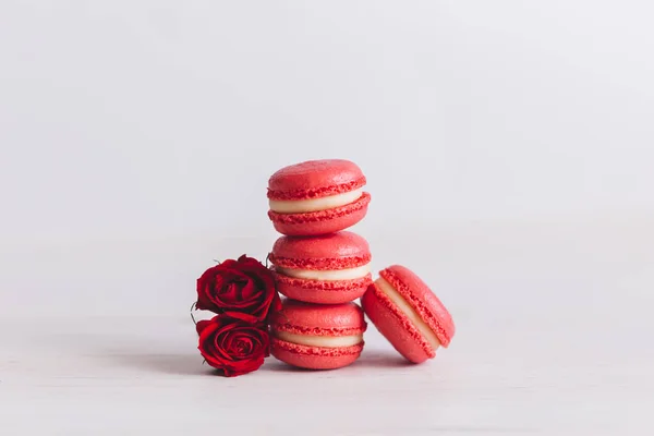 Tasty french macaroons with red roses on a white background.  Place for text.