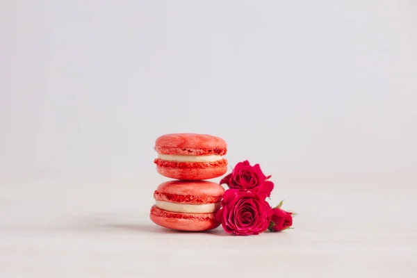 Tasty french macaroons with pink roses on a white background.  Place for text.