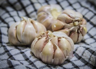 Mutfak örtüsünün üstünde birkaç sarımsak soğanı var.