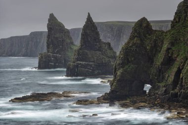 Düşük hızlı bir fotoğraf dalgaların hareketlerini Ducansby Head 'de John O' Groats, İskoçya yakınlarında bulutlu bir akşamda deniz yığınlarına çarptığını gösteriyor.. 