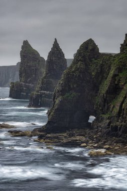 Düşük hızlı bir fotoğraf dalgaların hareketlerini Ducansby Head 'de John O' Groats, İskoçya yakınlarında bulutlu bir akşamda deniz yığınlarına çarptığını gösteriyor.. 