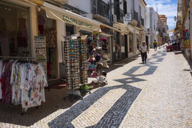 Lagos, Portekiz - 27 Haziran 2018: Turistler güneşli bir günde Lagos 'un fayanslı caddeleri boyunca sıralanmış mağazalarda durdular. 