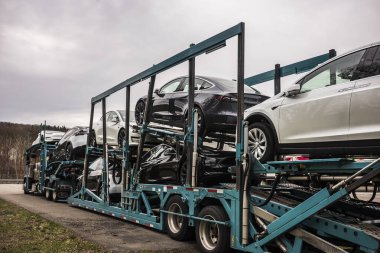 Vestal, New York / ABD - 11 Nisan 2020: 7 Tesla Modeli taşıyan yarı izci karavanı, beyaz, siyah ve gümüşe boyanmış, Paskalya haftasonu boyunca bir otoparkta park halinde duruyor.. 
