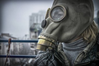 Arka planda sis ve kirlilik olan gaz maskeli orta yaşlı bir kadın.
