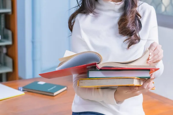 Genç Asyalı kız öğrenci portresi oturur ve üniversite kütüphanesinde sınavlara ya da sınavlara hazırlanmak için ders kitabı okumaya konsantre olur. Eğitim bilgisi ve öğrenme kavramı.
