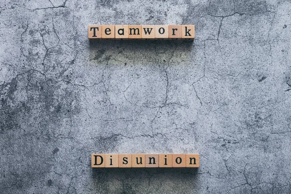 Wood cube letter word of Disunion and Teamwork. Idea of motivation or inspiration in business vision and corporate management strategy. Leadership lead team to reach goal or achievement.