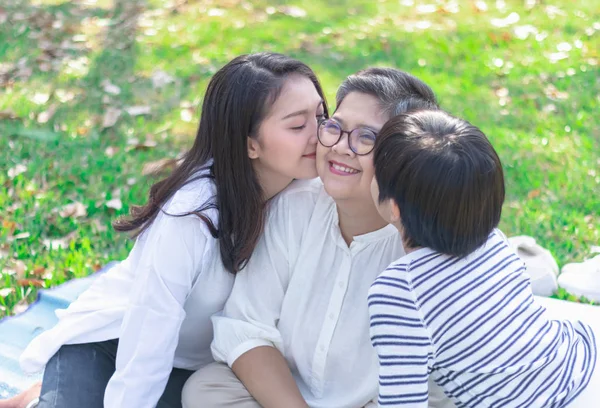 Asyalı sevimli genç kız ve torun mutlu ve sağlıklı yaşlı bir kadını öperler ya da parkta güzel bir aşk anında büyükanneyi memnun ederler. Aile üretimi ilişkisi ya da fotoğraf konsepti