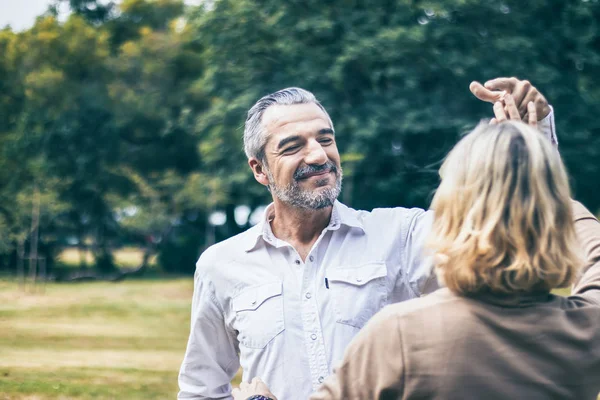 Lovely senior elderly smiling couple man and woman dancing in the park in romantic moment. Warm heart marriage and lover bonding and relationship. Husband and wife in love. Happy retired people photo