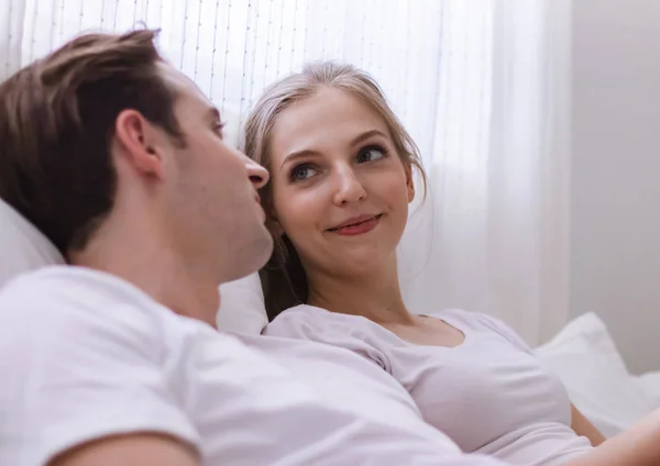 Happy young caucasian couple or lover on bed together. Man read book for woman in dreamy romantic moment in bedroom. Photo of married relationship or bonding between husband and wife in Valentine day