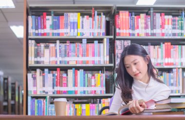 Genç Asyalı gülümseme kız öğrenci portresi oturan ve konsantre olan