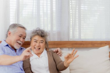 Asyalı, mutlu, emekli, yaşlı, gülümseyen ve evde birlikte gülen sevimli bir çift. Emeklilikten sonra mutlu bir yaşam tarzı olan güzel bir evlilik aşığının romantik ilişkisi.