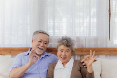 Asyalı, mutlu, emekli, yaşlı, gülümseyen ve evde birlikte gülen sevimli bir çift. Emeklilikten sonra mutlu bir yaşam tarzı olan güzel bir evlilik aşığının romantik ilişkisi.