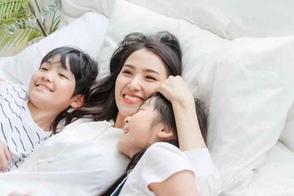 Mutlu Asyalı aile gülümseyen anne, oğul ve kız yatak odasında. Anne, oğul ve kız evde iyi vakit geçirin. Anne ve çocuklar arasındaki aşk ilişkisi ya da bağ. Halk yaşam tarzı konsepti
