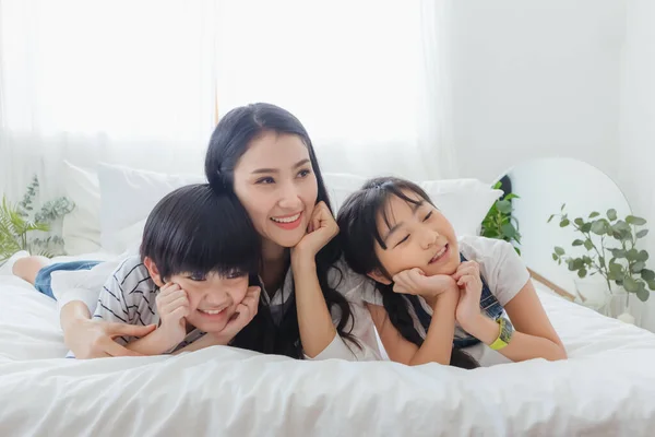 Lovely happy Asian family at cozy home. Smiling mother, son and daughter enjoy ,relax and playful together in bedroom. Happiness relationship and bonding of love between parent and children moment