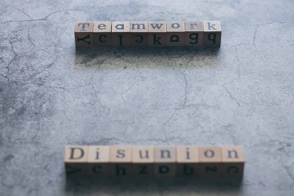 Wood cube letter word of Disunion and Teamwork. Idea of motivation or inspiration in business vision and corporate management strategy. Leadership lead team to reach goal or achievement.