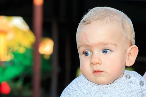 A nine-month-old boy with blond hair and blue eyes. A beautiful nine-year-old baby. Blurred background. Close up. — Stock Photo, Image