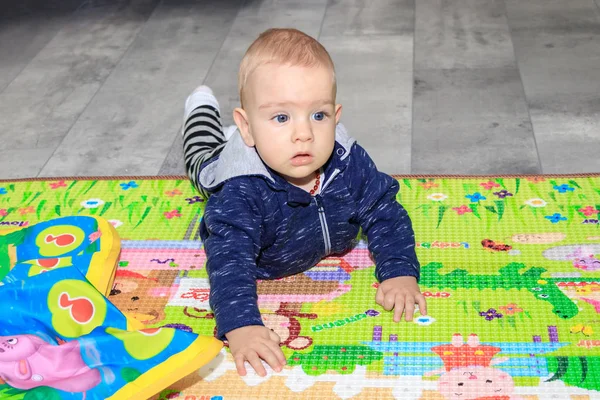 Malý chlapeček se plazí po podlaze doma. Devítiměsíční chlapec s blond vlasy a modrýma očima. — Stock fotografie