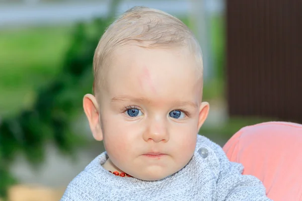 Devítiměsíční chlapec s blond vlasy a modrýma očima se zamyšleně dívá do dálky — Stock fotografie