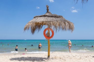 Hayat kurtaran ekipmanlı sahil şemsiyesi ve arka planda turist bulunan Akdeniz