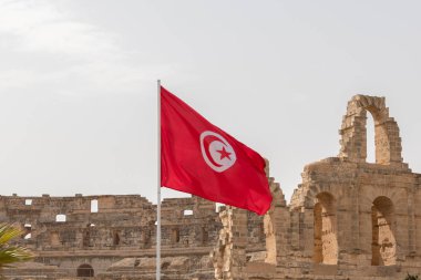 Arka planda Tunus 'un kırmızı ve beyaz bayrağı El Jem, Tunus ve Afrika Roma amfitiyatrosunun kalıntılarıdır.