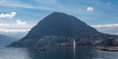 Göldeki çeşme ve Lugano Gölü ve Monte San Salvatore, İsviçre manzaralı bir balıkçı teknesi.