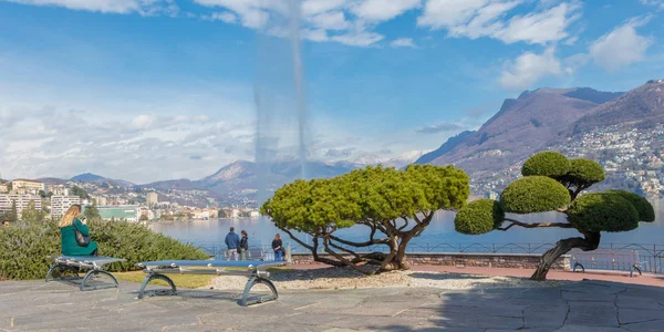 Lugano, Switzerland - March 10, 2019: A woman sitting on a bench at the promenade, Lake Lugano, Ticino, Switzerland — Stock Photo, Image