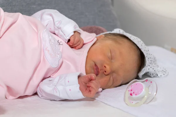 Neugeborenes Mädchen in einem rosafarbenen Schlafanzug. das kleine Mädchen ist 15 Tage alt. — Stockfoto