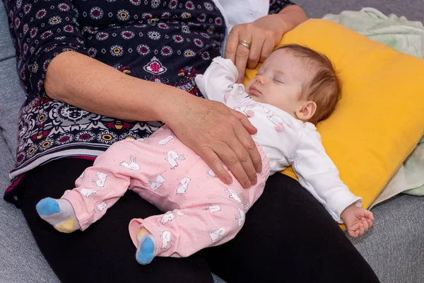 Bebek büyükannenin kollarında uyuyor. Bebek iki aylık..