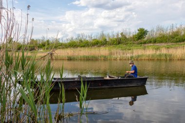 Sırbistan 'ın Novi Sad kenti yakınlarındaki Tuna-Tisa-Tuna kanalında bir teknede kıdemli balıkçı.
