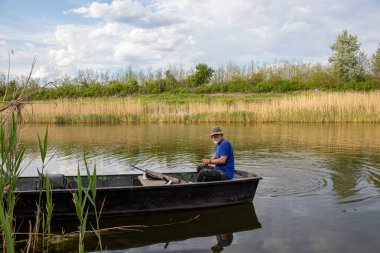 Sırbistan 'ın Novi Sad kenti yakınlarındaki Tuna-Tisa-Tuna kanalında bir teknede kıdemli balıkçı.