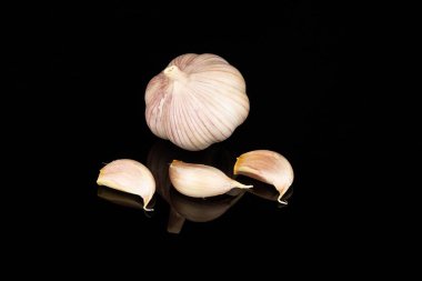 Yansımalı siyah ayna yüzeyinde taze sarımsak baş ve karanfilleri