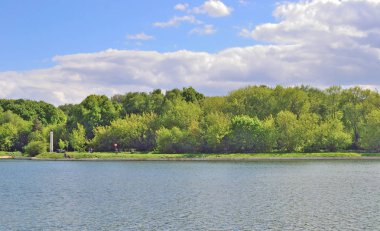 Bir su birikintisi bir şehir parkı karşı kıyıda