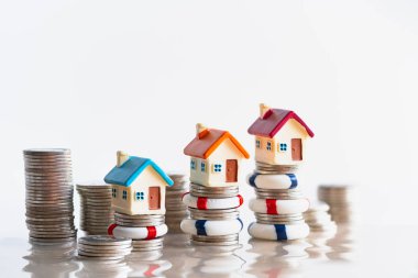 Ev sigortası konsepti. Bozuk paraların üzerinde yaşam şamandıraları içinde ev modeli. Sigortalı bir ev sigortası yaparak evin büyük bir değerini sağlama almak. Sel baskını gibi tehlikelerden korunmak için yapısal risk.