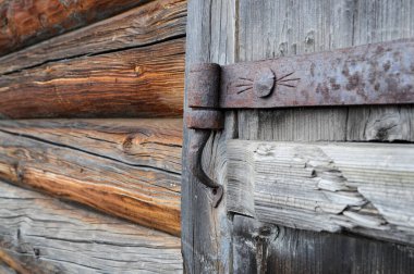 Pasla kaplı eski bir demir kapı menteşesi eski bir ahşap kapıya asılı.