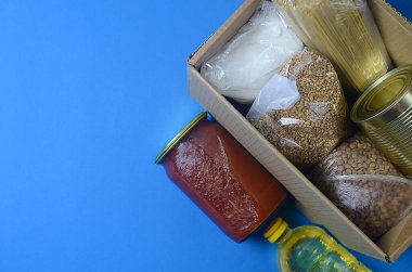 Mısır gevreği, şeker, tereyağı, domates ezmesi, mavi arka plandaki bir kutuda spagetti.