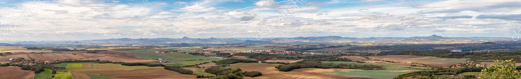 rural landscape panorama with villages, fields and mountains in the background, blue sky with white clouds, view from Rip mountain, Ceske stredohori, Czech republic