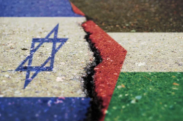 Flags of Israel and Palestine on asphalt are separated by a crack.