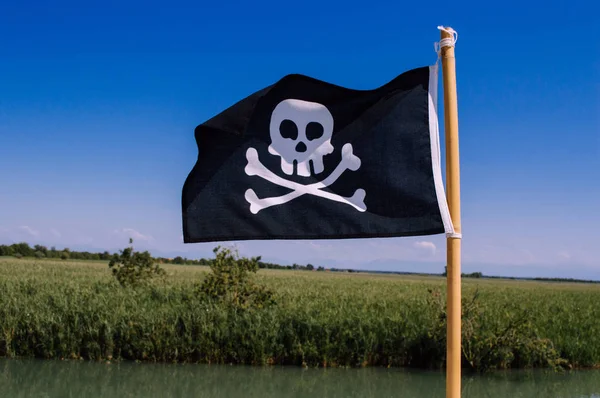 Μαύρη πειρατική σημαία με νεκροκεφαλή και σταυρωτά κόκαλα — Φωτογραφία Αρχείου