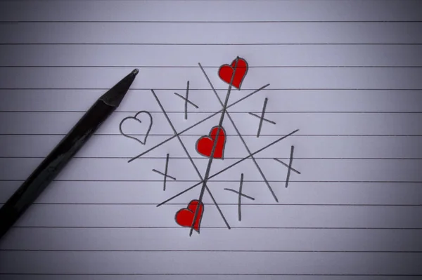 Tic-tac-toe game with a crossed line and hearts drawn on paper — Stock Photo, Image